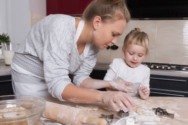 Mutlu bir aile! Küçük bir kızı kurabiye pişirmeye annesi ile mutfakta vakit geçiriyor. Anneler günü.