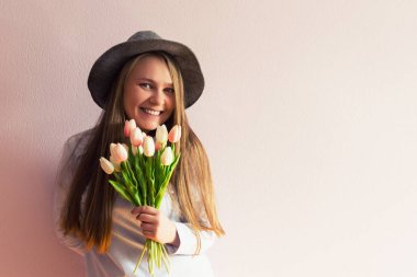 Sarı çözünmüş uzun saçlı, keçe şapka başında, güzel bir genç kızla bahar çiçekleri güneşli bir günde elinde tutar. Kadınlar günü.