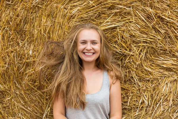 干し草の背景に乱れた髪をブロンドに笑顔の若い女性 領域をコピーします 厄介な髪のコンセプト — ストック写真