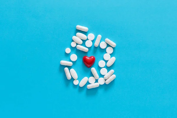 Corazón Rojo Rodeado Diferentes Tabletas Blancas Sobre Fondo Azul Sólido — Foto de Stock