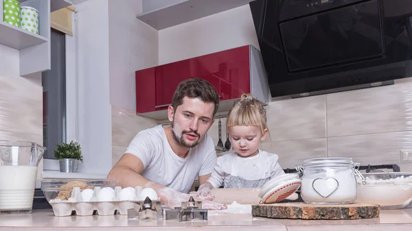 Fathers day! A tiny sweet girl with blond hair spends time with her dad, cooking in the kitchen. Preparations for the holidays. Baking.