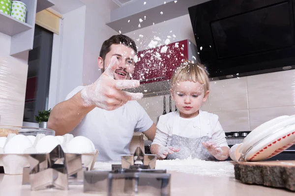 Fathers day! A tiny sweet girl with blond hair spends time with her dad, cooking in the kitchen. Preparations for the holidays. Baking.