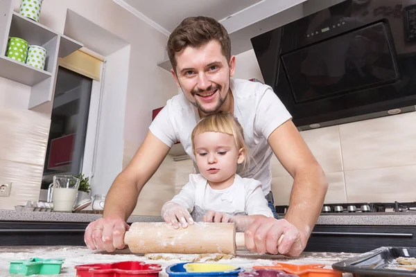 Fathers day! A tiny sweet girl with blond hair spends time with her dad, cooking in the kitchen. Preparations for the holidays. Baking.