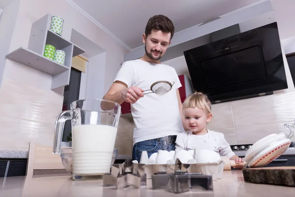 Fathers day! A tiny sweet girl with blond hair spends time with her dad, cooking in the kitchen. Preparations for the holidays. Baking.