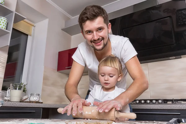 Fathers day! A tiny sweet girl with blond hair spends time with her dad, cooking in the kitchen. Preparations for the holidays. Baking.