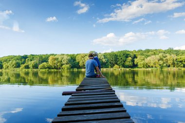 Baba ve kaba pamuklu Tulum içinde küçük bir kız nehirde rahatlayın. Arkadan görünüm, kopya alanı.