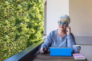 Sarışın saçlı güzel kadın kıdemli bir iş evde çalışır. Teras manzarası. Güneşli gün.