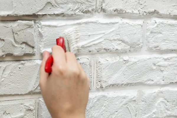 ladies hand painted brick brush white wall. Renovation work. White background.