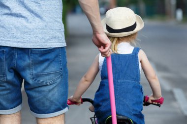 Babası kızı Bisiklete binmeyi öğretiyor.