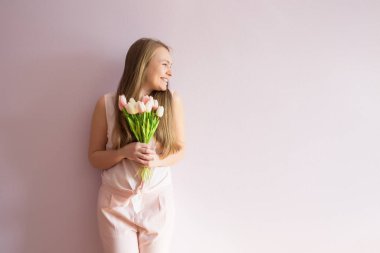 Sarı çözünmüş uzun saçlı, keçe şapka başında, güzel bir genç kızla bahar çiçekleri güneşli bir günde elinde tutar. Kadınlar günü.