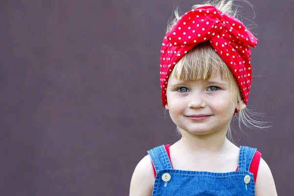 Little girl with polka-dot headband laughs and looks at the viewer. Copy space.