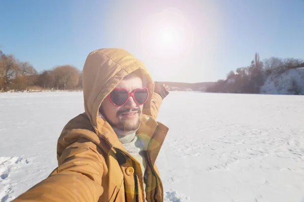 Hombre barbudo feliz con gafas de sol en un clima soleado y nevado concepto  de pasar tiempo activo caminando después de una ventisca de nieve el tipo  sonriendo y usando una chaqueta de invierno