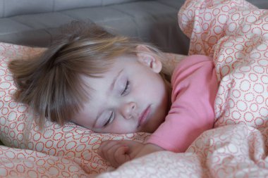 Küçük kız anne babamın yatağında uyuyor. Bir gün seçici odak uyuyor.