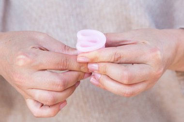 Adet Kupası kadın eliyle tutuyor. Seçici odak.