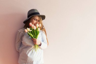 Sarı çözünmüş uzun saçlı, keçe şapka başında, güzel bir genç kızla bahar çiçekleri güneşli bir günde elinde tutar. Kadınlar günü.