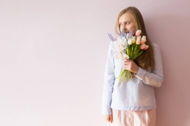 Sarı çözünmüş uzun saçlı, keçe şapka başında, güzel bir genç kızla bahar çiçekleri güneşli bir günde elinde tutar. Kadınlar günü.