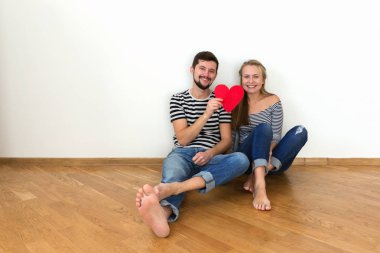 Elinde kırmızı bir kalp ile katta oturan aşık bir çift