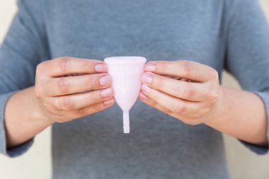 Adet Kupası kadın eliyle tutuyor. Seçici odak.