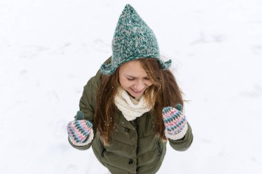 Uzun sarı saçlı güzel bir genç kızla ilk kar sahiptir. Yeşil ceket, yeşil şapka ve eldiven. Üstten görünüm. Kopya alanı.