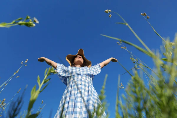 一个穿着蓝色连衣裙和草帽的女人站在田野里 握住她的手 生活没有过敏的概念 — 图库照片