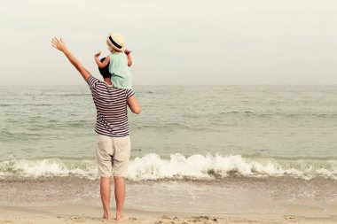 Baba ve kızı plajda durup ve denize bakmak. Arkadan görünüm, kopya alanı.