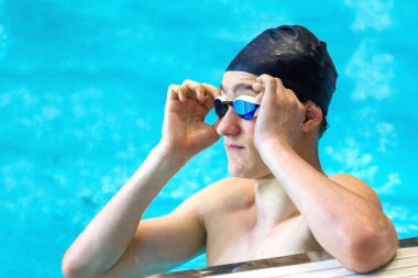 Genç bir atlet kapalı havuzda yüzme gözlüklerini geliştirir. Yaklaş, seçici odaklanma.
