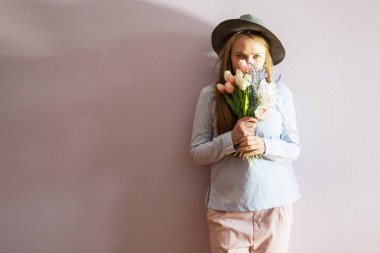 Sarı çözünmüş uzun saçlı, keçe şapka başında, güzel bir genç kızla bahar çiçekleri güneşli bir günde elinde tutar. Kadınlar günü.