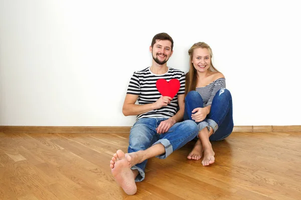 Happy valentines couple sitting on a wooden floor. White background copy space