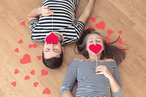 Young happy valentines couple lying on the floor with closed eyes.