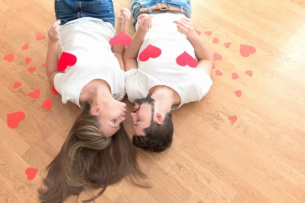 Young happy valentines couple lying on the floor and kissing. Toned, copy space.