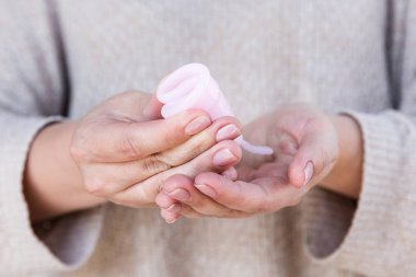 Adet Kupası kadın eliyle tutuyor. Seçici odak.