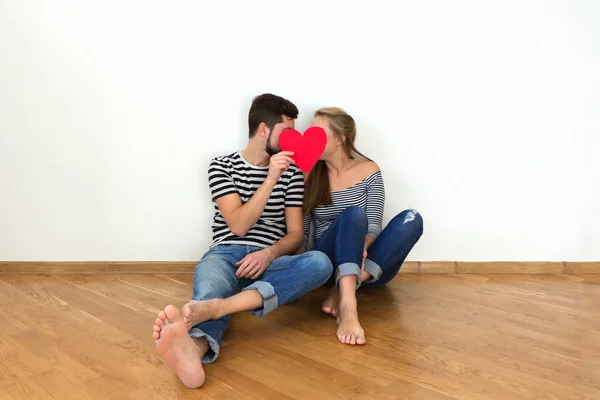 Happy valentines couple sitting on a wooden floor. White background copy space.