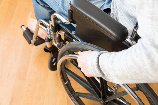 Detail of disabled man hand holding wheel of a wheelchair.