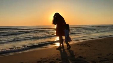 Anne ve kızı kumsalda yürüyor..