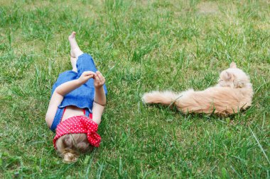 Güneşli bir günde bir kırmızı kedi ile oynarken küçük kız. Kopya alanı. 
