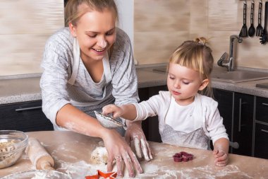 Mutlu bir aile! Küçük bir kızı kurabiye pişirmeye annesi ile mutfakta vakit geçiriyor. Anneler günü.