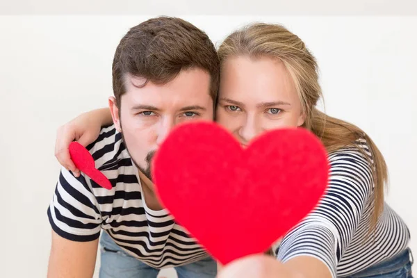 Funny couple covered faces with red heart. Valentines concept.