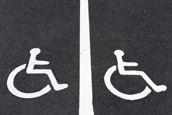 Disabled sign painted on grey asphalt.