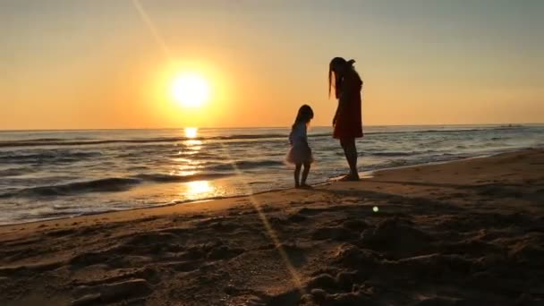 Μητέρα και κόρη το περπάτημα κατά μήκος της παραλίας στο ηλιοβασίλεμα. — Αρχείο Βίντεο