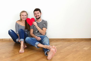 Elinde kırmızı bir kalp ile katta oturan aşık bir çift