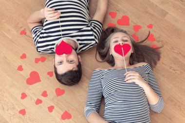 Üstten görünüm genç çift yerde yatarken ve kamera ve gülümseme için arıyorum.