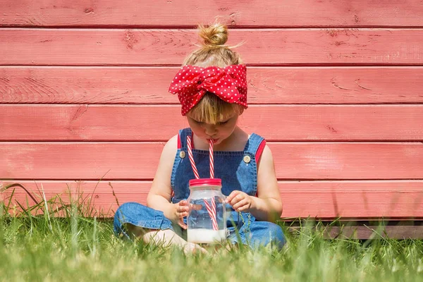 Liten Flicka Blå Hängselbyxa Sitter Och Dricker Mjölk Trädgården Sommartid — Stockfoto