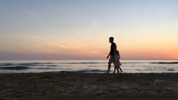 Otec a dcera, procházky po pláži při západu slunce. — Stock video
