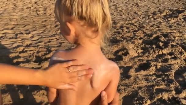 Woman hand smears little girl back with sunscreen. — Stock Video