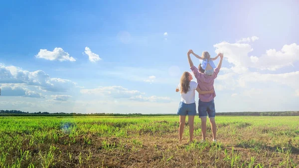 Mutlu bir aile. Anne baba ve kızı buğday alan güneşte bakmak. Arkadan Görünüm.