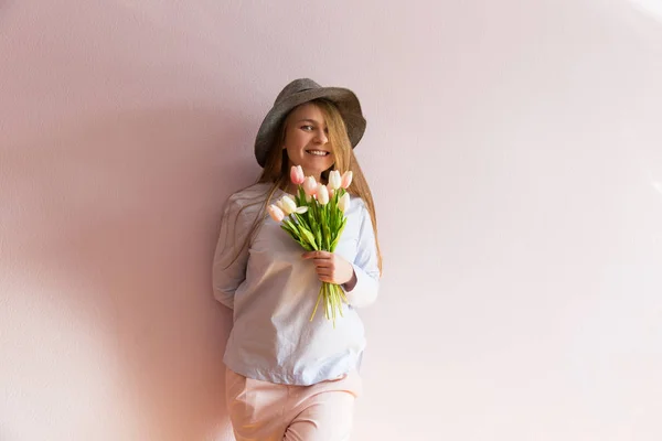 溶存長い金髪 彼女の頭の上にフェルト帽子の美しい少女は 彼女の手で晴れた日に春の花を保持します 女性の日 — ストック写真
