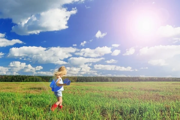 Маленька дівчинка тримає паперовий літак в руці і бігає в літаку — стокове фото