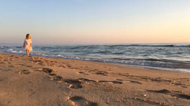 日落时 一个小女孩沿着海滩奔跑 — 图库视频影像