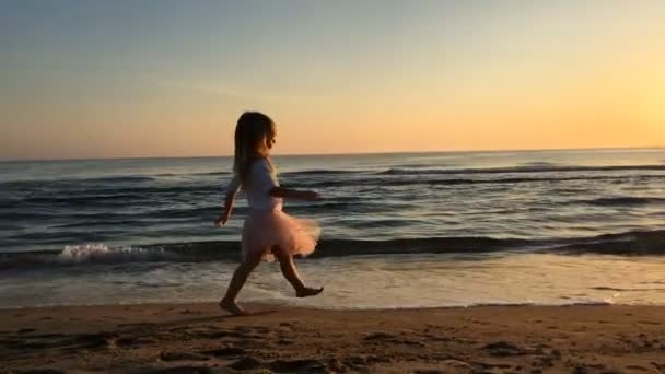 Klein meisje loopt naar haar moeder op het strand bij zonsondergang. — Stockvideo