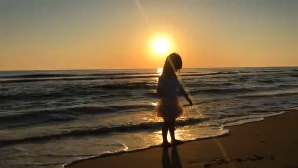 Kleines Mädchen tanzt am Strand bei Sonnenuntergang. — Stockvideo